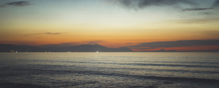 Clouds blue sky and gold sunlight sunset on horizon ocean, background seascape dramatic atmosphere rays sunrise. Relax view waves sea with ship, mockup nature evening concept, copy space for textの写真素材