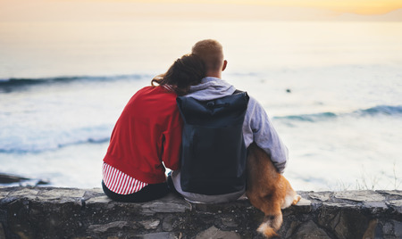 Couple hugging on background beach ocean sunrise, silhouette two romantic people cuddling and looking on rear view evening seascape, hipster with dog enjoy sunset together, travel holidays vacation, love relax conceptの写真素材