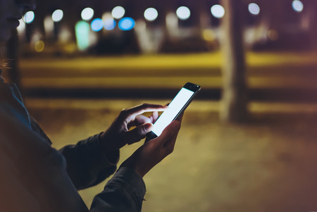 Woman pointing finger on screen smartphone on background illumination bokeh light in night...