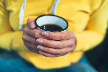 girl holding in hands cup of hot tea on yellow backgroung in outdoors nature park, beautiful woman hipster enjoy drinking cup of coffee closeup, lifestyle relax recreation meditation conceptの写真素材