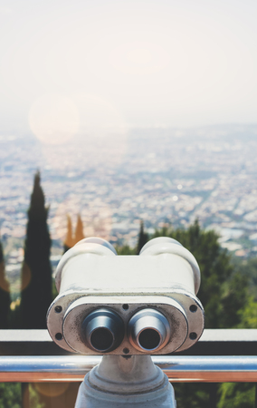 Touristic telescope look at the city with view of Barcelona Spain, close up old metal binoculars on background viewpoint overlooking the mountain, hipster coin operated in panorama observation nature blue sky, mockup flareの写真素材