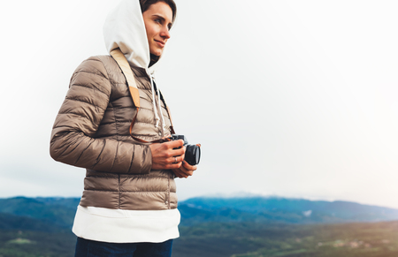 photographer traveler on green top on mountain, tourist looking enjoy nature panoramic landscape in trip, girl holding in hands digital photo camera, hiker taking click photography, relax holiday hobby conceptの写真素材