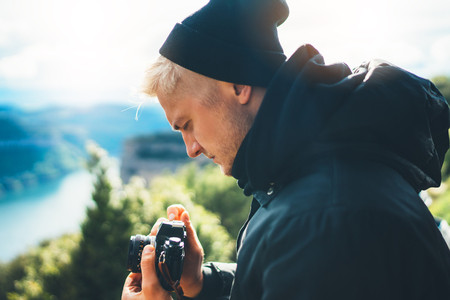 hipster tourist hold in hands taking photography click on retro vintage photo camera in auto, photographer looking on camera technology, blogger using hobby content, vacation weekend conceptの写真素材