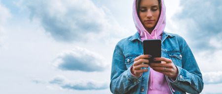 tourist young girl on background blue sky using mobile smartphone, person holding in female hands...