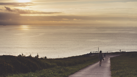 Clouds sky and sunlight sunset on horizon ocean. People on background seascape dramatic atmosphere rays sunrise. Relax view waves water sea, mockup nature evening concept perspective ocean sunriseの写真素材
