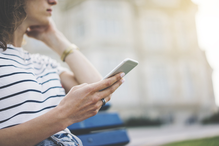 Hipster texting message on smartphone or technology, mock up of blank screen. Girl using cellphone on building castle background close. Tourist female hands holding gadget on blurred backdrop. Mockup side viewの写真素材