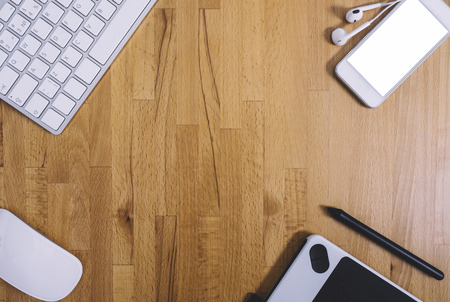 Top view of a keyboard, mouse, graphics tablet, headphones and smartphone with empty blank screen on a background wooden table, blank for your text or content or design, closeup, free space. Mock up top viewの写真素材