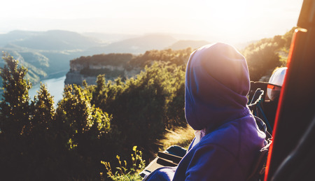 tourist traveler on background top mountain sits and enjoys the sunset, hiker looking on blue sky clouds, nature panoramic landscape in trip, relax holiday mockup concept in trekking tripの写真素材