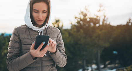 girl hold in hands mobile phone, person type message on smartphone, relax tourist travels planning trip in snow mountain, hipster enjoy winter nature, journey landscape trip, lifestyle holiday conceptの写真素材