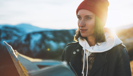 young girl look and hold in hands map, people planning trip, hipster tourist on background sun flare nature, enjoy journey landscape vacation trip, lifestyle holiday concept, sun mountainの写真素材