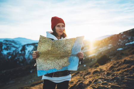 young girl look and hold in hands map, people planning trip, hipster tourist on background sun flare nature, enjoy journey landscape vacation trip, lifestyle holiday concept, sun mountainの写真素材