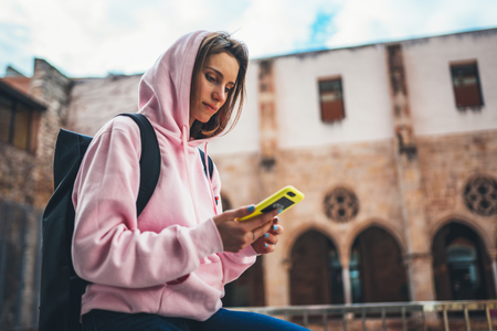girl hold in hands mobile phone, person type message on smartphone, relax tourist travels planning trip in city, hipster enjoy journey in cityscape, lifestyle holiday concept, internet onlineの写真素材