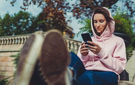 girl hold in hand mobile phone, person type message on smartphone, relax tourist travels planning trip in sun city, hipster enjoy journey in cityscape, lifestyle holiday conceptの写真素材