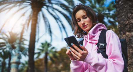 girl hold in hands mobile phone, person type message on smartphone, relax tourist travels planning trip in sun city, hipster enjoy journey in cityscape, lifestyle holiday concept, internet onlineの写真素材