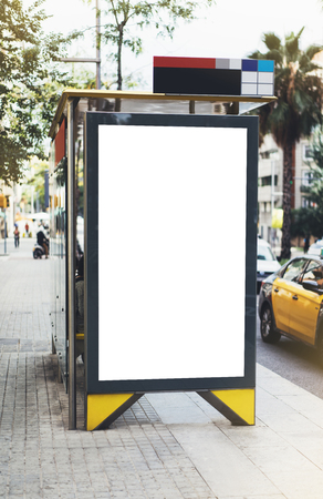 Blank advertising light box on bus stop, mockup of empty ad billboard on night bus station, template banner on background city street for message or text in Barcelona, afisha board and headlights of taxi carsの写真素材