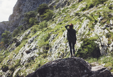 Happy tourist traveler standing on a rock, hiker looking to a valley below in trip in spain, hipster young girl enjoying peak of foggy mountain background green landscape view mockupの写真素材
