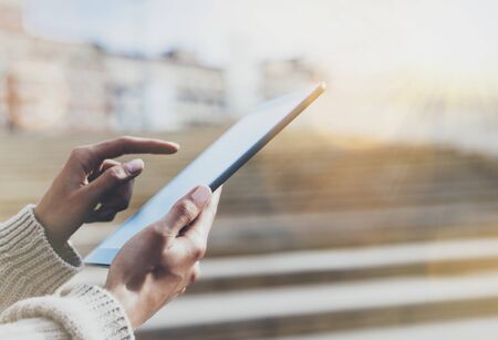 Hipster tourist texting message on tablet or technology mock up. Person using computer on building background close. Female hands holding gadget on blurred backdrop mockup. Copy space for text message or designの写真素材