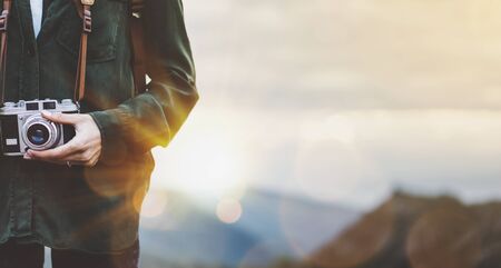 Hipster young girl with bright backpack taking photo of amazing landscape sunset on vintage camera close on peak of foggy mountain mockup. Tourist traveler on background sunlight in trip in northern spain basque country, mock up for text.の写真素材