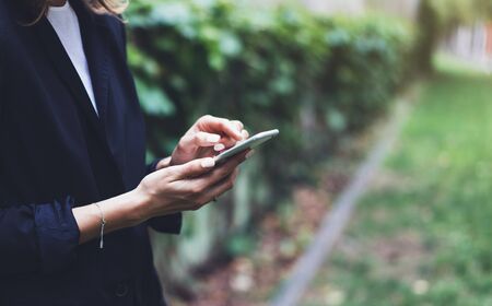 Portrait young businesswomen in black suit using smartphone isolated on background green nature wall mockup, pretty hipster manager holding mobile gadget, girl smile and texting message, connectの写真素材
