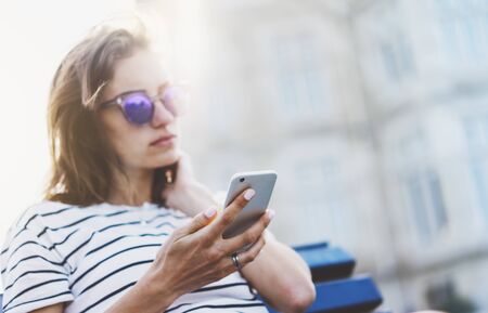 Hipster texting message on smartphone or technology, mockup of blank screen. Girl using cellphone on building castle background close. Tourist female hands holding gadget on blurred summer backdropの写真素材