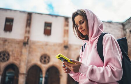 girl hold in hands mobile phone, person type message on smartphone, relax tourist travels planning trip in city, hipster enjoy journey in cityscape, lifestyle holiday concept, internet onlineの写真素材