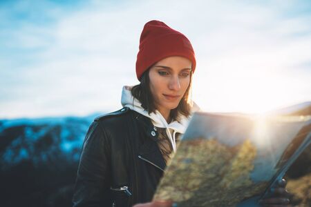 young girl look and hold in hands map, person planning trip, hipster tourist on background sun flare nature, enjoy journey landscape vacation trip, lifestyle holiday concept, sun mountainの写真素材