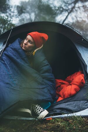 tourist traveler ralaxing in camp tent in froggy rain forest, lonely hiker woman enjoy mist nature trip, green trekking tourism, rest vacation concept camping holidayの写真素材