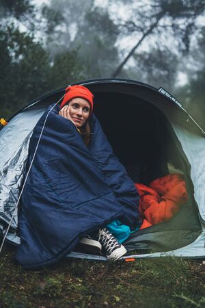 tourist traveler smile ralaxing in camp tent in froggy mist forest, lonely happy hiker woman enjoy nature trip, green trekking tourism, rest vacation concept camping holidayの写真素材