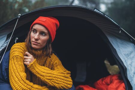 tourist traveler ralaxing in camp tent in froggy rain forest, closeup lonely hiker woman enjoy mist nature trip, green trekking tourism, rest vacation concept camping holidayの写真素材