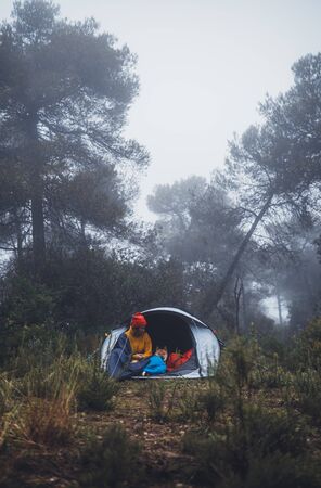 tourist traveler relaxation red shiba inu in camp tent on background froggy forest, hiker woman with puppy dog in blue mist nature trip, friendship love concept, girl resting dog togetherの写真素材
