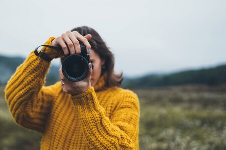 photographer girl take photo on camera on background autumn froggy mountain, tourist shooting nature mist landscape, hobby concept, copy spaceの写真素材