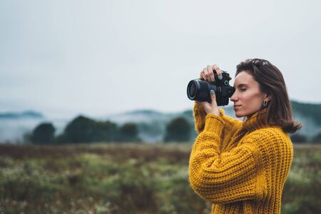 photographer traveler take photo on video camera closeup on background autumn froggy mountain, tourist shooting nature mist landscape outdoor, hobby concept copy space mockupの写真素材