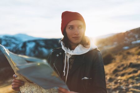 young girl look and hold in hands map, people planning trip, hipster tourist on background sun flare nature, enjoy journey landscape vacation trip, lifestyle holiday concept, sun mountainの写真素材