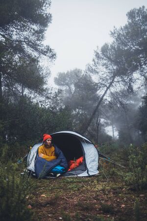 tourist traveler ralaxing in camp tent in froggy rain forest, closeup lonely hiker woman enjoy mist nature trip, green trekking tourism, rest vacation concept camping holiday, copy spaceの写真素材