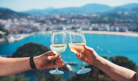 Drink two glasses white wine in friends hands outdoor sea nature holidays, romantic couple toast with alcohol, happy people cheering fun vacation enjoy travel time together friendship love concept congratulationsの写真素材