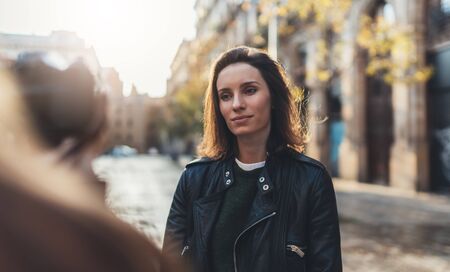 Photographer with camera take photo model girlfriend. Tourist smiling girl in hat travels in Barcelona holiday with traveler friend. Sunlight flare street in europe city. Photoshoot conceptの写真素材