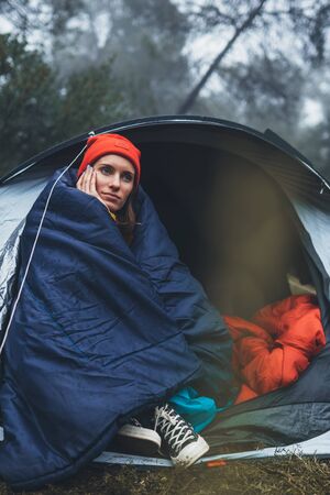 tourist traveler ralaxing in camp tent in froggy rain forest, closeup lonely hiker woman enjoy mist nature trip, green trekking tourism, rest vacation concept camping holiday, hiking campsite    の写真素材