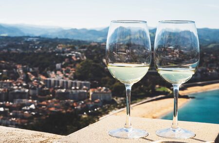 Two drink glass white wine standing on background blue sea top view city coast yacht from...