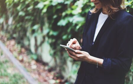 Portrait young businesswomen in black suit using smartphone isolated on background green nature wall mockup, pretty hipster manager holding mobile gadget, girl smile and texting message, connectの写真素材