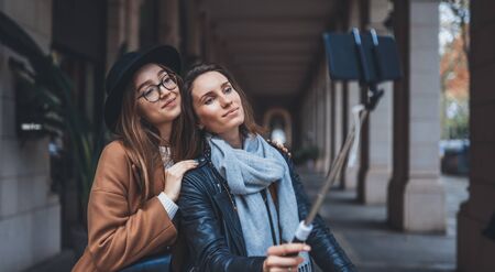 Girlfriends tourist taking photo selfie together on smartphone mobile. Blogger hipster travels in europe city. Vacation holiday friendship concept. Travelers self on cellphone internet technology mockup spaceの写真素材
