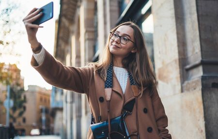 Smile traveler in glasses self cellphone internet technology in europe trip. Tourist girl taking photo selfie on smartphone mobile. Blogger hipster travels in Barcelona. Holiday communication conceptの写真素材