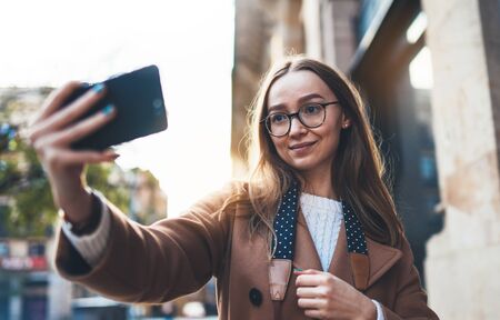 Traveler in glasses self cellphone portrait internet technology in europe trip. Tourist girl taking photo selfie on smartphone online mobile. Blogger hipster travel in Barcelona. Holiday communicationの写真素材