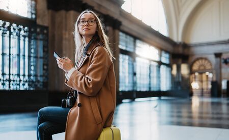 Tourist woman holding mobile smartphone on platform station in Barcelona. Girl traveler waiting train using online gadget cellphone. Holiday vacation in transport railway. Digital wifi internetの写真素材