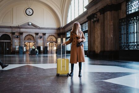 Tourist woman with suitcase retro camera on platform station in Barcelona. Girl traveler waiting train enjoy holiday weekend vacation in transport railway. Travel railroad station conceptの写真素材