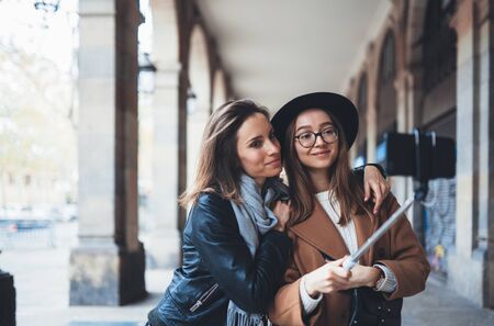 Positive girlfriends taking photo selfie on smartphone mobile. Blogger hipster travels in Barcelona....