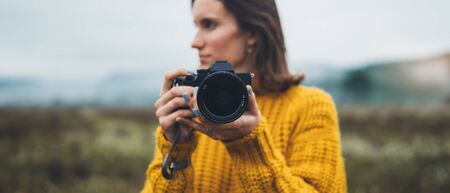 photographer traveler take photo on video camera closeup on background autumn foggy mountain, tourist shooting nature mist landscape, copy space mockupの写真素材
