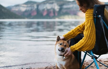 tourist traveler girl relax tender together friends dog on background mountain landscape,  woman hugging pet rest on lake shore nature tripの写真素材