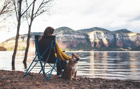 tourist traveler girl relax together dog on background mountain, puppy pet with woman rest on lake shore nature trip, friendship conceptの写真素材
