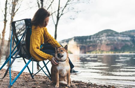 tourist traveler girl relax tender together friends dog on background mountain landscape,  woman hugging pet rest on lake shore nature tripの写真素材