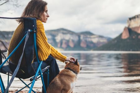 tourist traveler girl relax together dog on foggy mountain scape,  woman hug pet rest on lake shore nature tripの写真素材